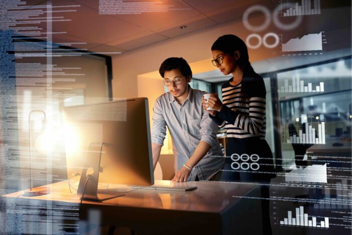 Shot of colleagues connecting to a user interface while working in an office at night.